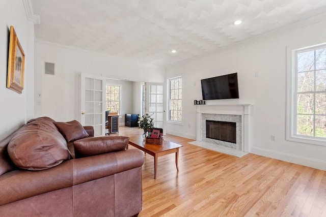living room featuring ornamental molding, recessed lighting, a premium fireplace, light wood-type flooring, and baseboards