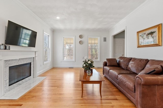 living room featuring light wood-type flooring, ornamental molding, a high end fireplace, and baseboards