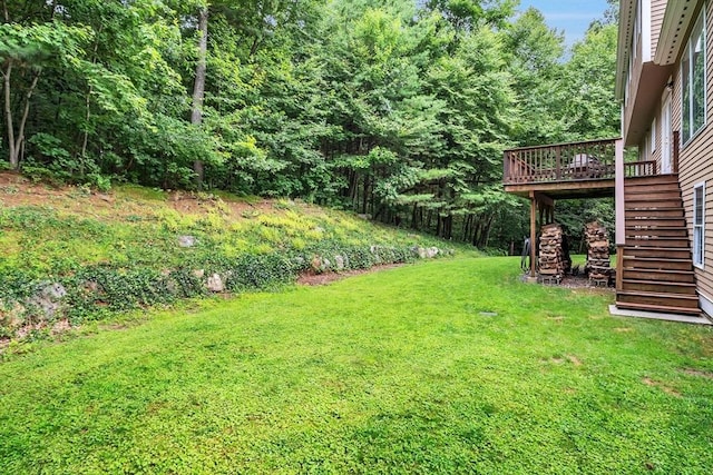 view of green lawn featuring stairway and a deck