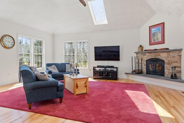 living area featuring lofted ceiling, wood finished floors, healthy amount of natural light, a skylight, and a fireplace