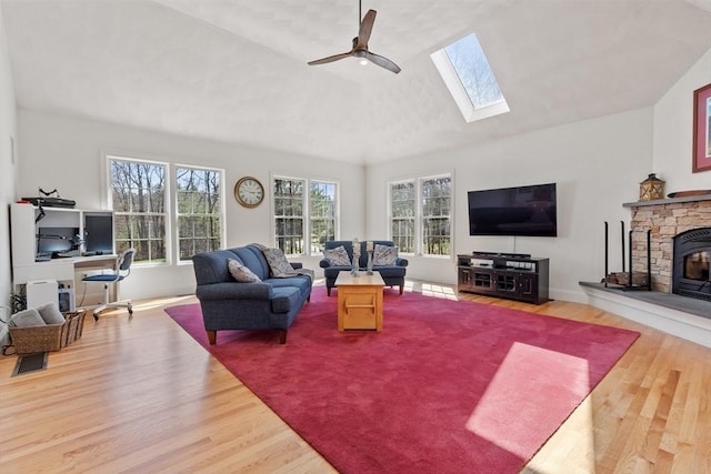 living room featuring vaulted ceiling, wood finished floors, a skylight, a desk, and ceiling fan