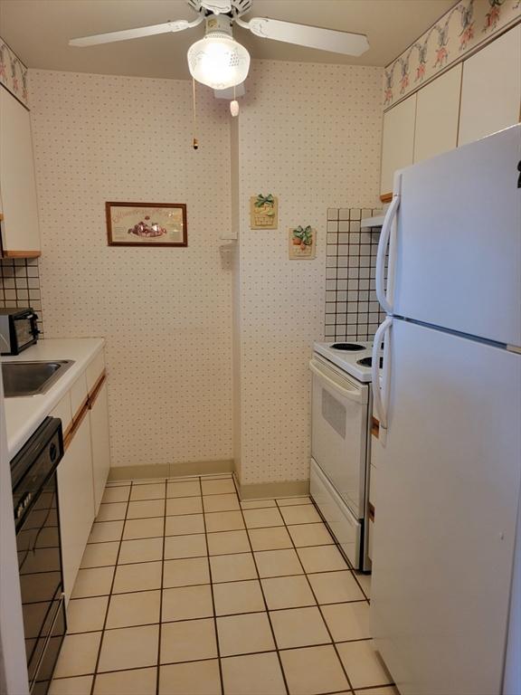 kitchen with white cabinets, light countertops, a ceiling fan, and white appliances