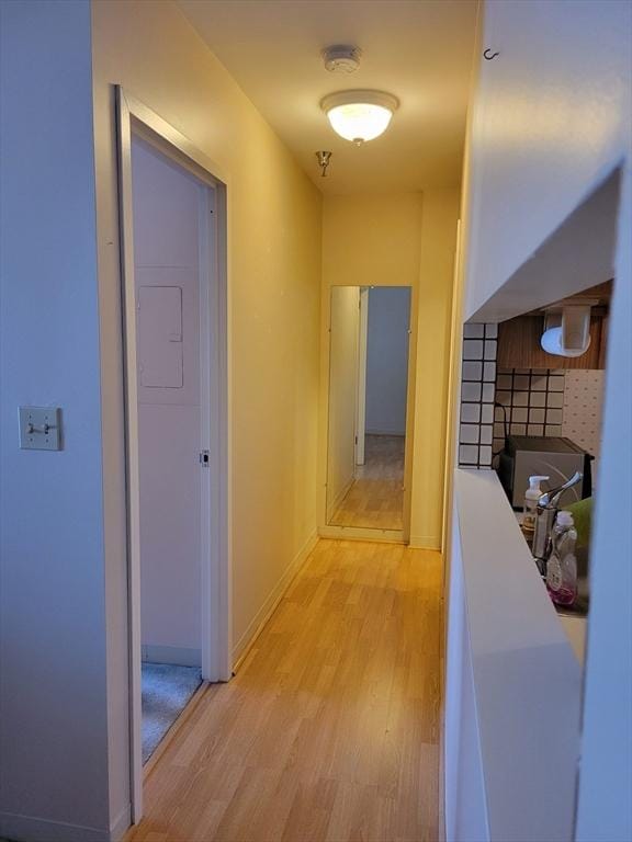 hallway featuring light wood-type flooring and baseboards