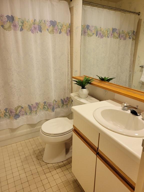 bathroom featuring wallpapered walls, tile patterned flooring, toilet, vanity, and shower / bath combo with shower curtain
