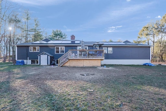 back of property with a storage shed, a wooden deck, and solar panels