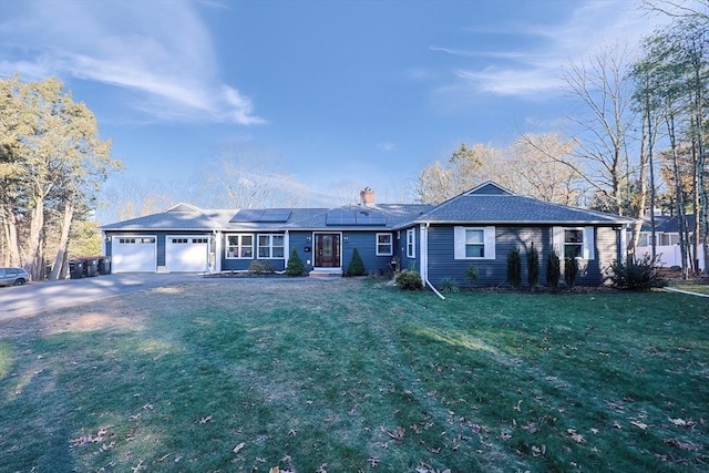 ranch-style home with solar panels, a garage, and a front lawn