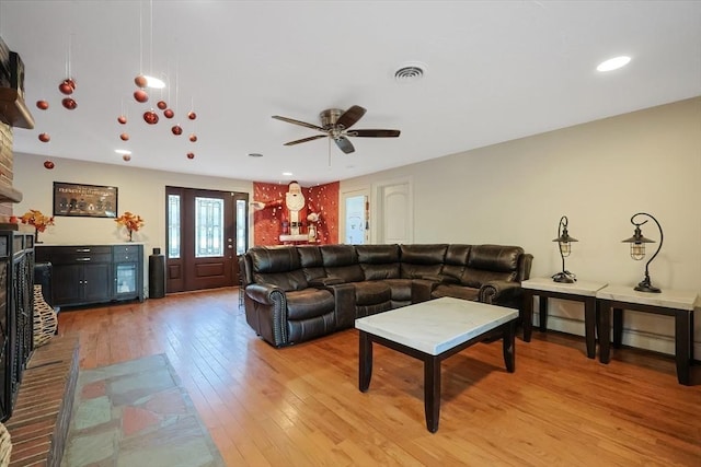 living room with light hardwood / wood-style floors, baseboard heating, and ceiling fan