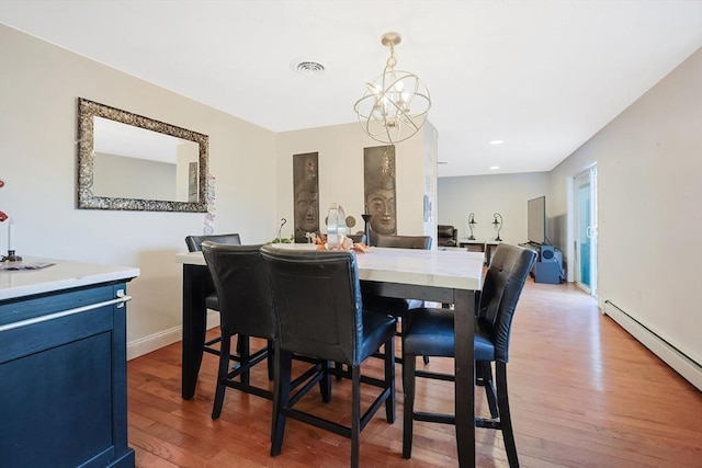 dining space with baseboard heating, hardwood / wood-style floors, and a chandelier