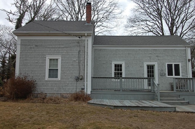 rear view of property featuring a deck, a shingled roof, and a chimney