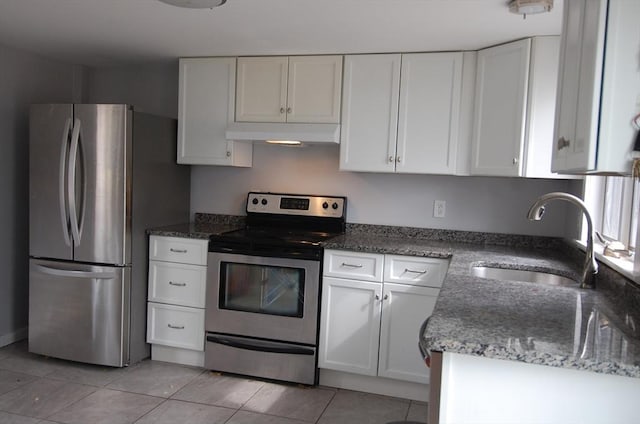 kitchen featuring stainless steel appliances, white cabinets, a sink, dark stone countertops, and under cabinet range hood