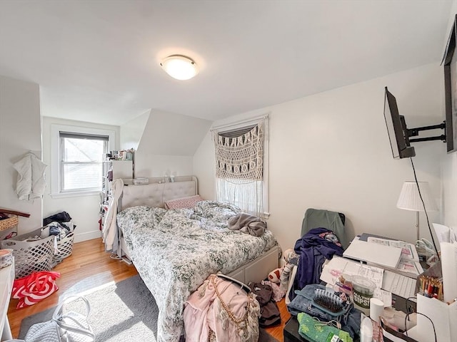 bedroom featuring baseboards, lofted ceiling, and wood finished floors