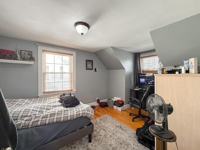 bedroom featuring vaulted ceiling, baseboards, and wood finished floors