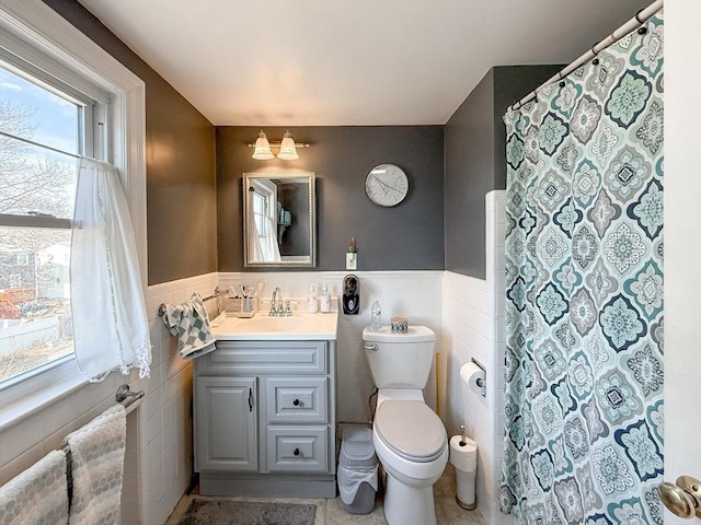 bathroom with a wainscoted wall, tile walls, and vanity