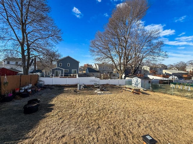 view of yard featuring a storage shed, a fenced backyard, and an outdoor structure