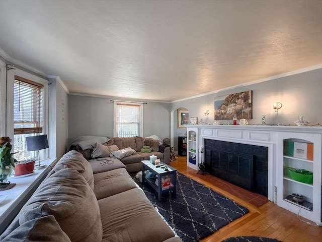 living area with a fireplace with flush hearth, crown molding, and wood finished floors