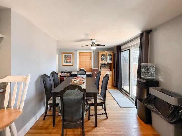 dining space featuring a ceiling fan, baseboards, and light wood finished floors