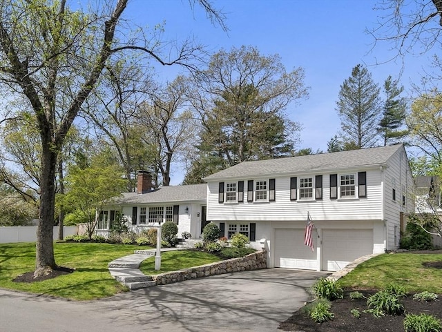 view of front of home featuring driveway, a chimney, and a garage