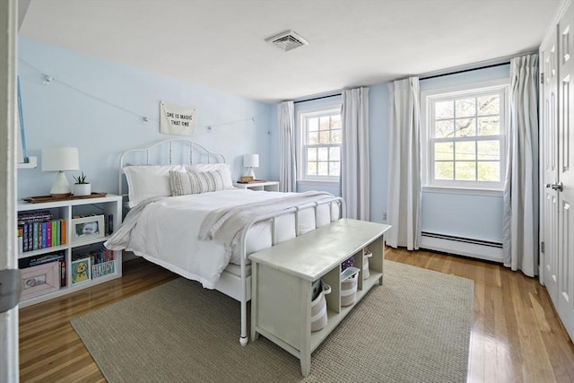 bedroom with baseboard heating and wood finished floors