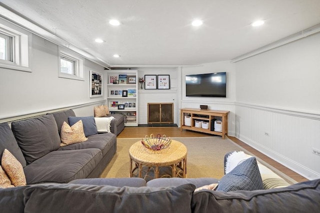 living area with wood finished floors, wainscoting, recessed lighting, and a fireplace