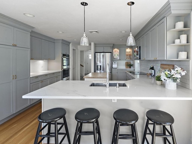 kitchen with gray cabinets, appliances with stainless steel finishes, a peninsula, a sink, and open shelves