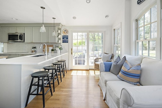 kitchen featuring a sink, stainless steel microwave, plenty of natural light, a breakfast bar, and recessed lighting