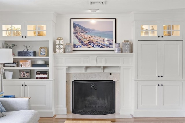 living room with ornamental molding, a fireplace, and light wood-type flooring