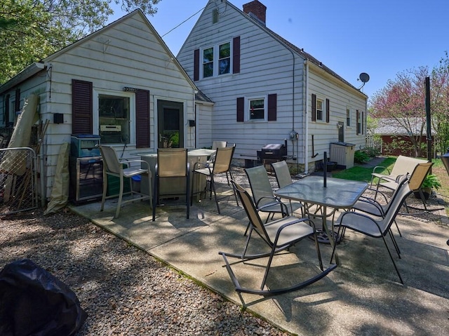 rear view of property with outdoor dining space, a patio, and a chimney