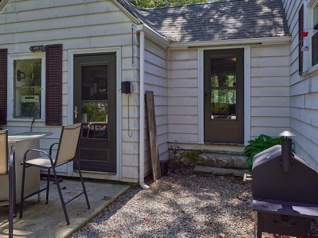 doorway to property with a shingled roof and a patio area