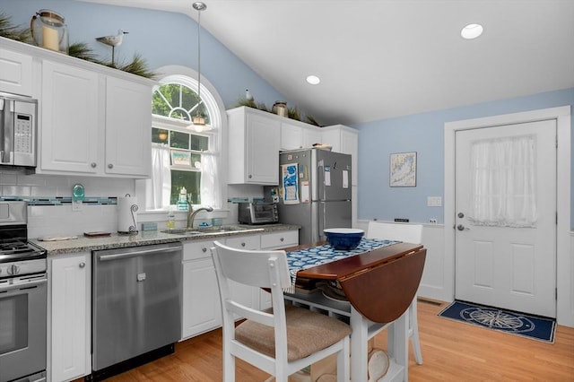 46 Pine, Falmouth, MA 02556 - kitchen featuring appliances with stainless steel finishes, vaulted ceiling, a sink, light wood-type flooring, and white cabinets