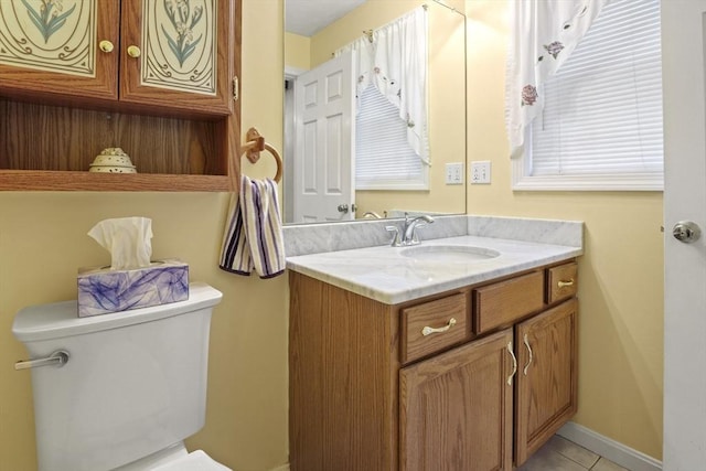 half bathroom featuring toilet, vanity, tile patterned floors, and baseboards