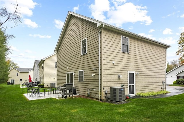 rear view of house with central AC, a lawn, and a patio