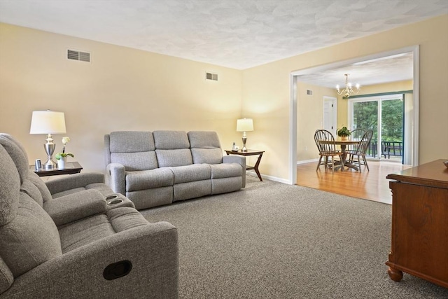 living area featuring carpet, a chandelier, baseboards, and a textured ceiling