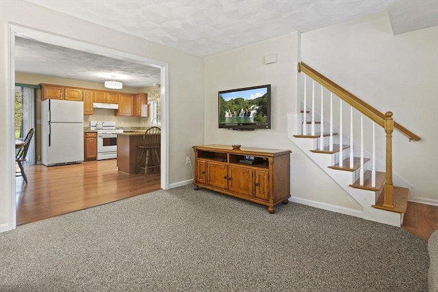 living area featuring light colored carpet, baseboards, and stairway