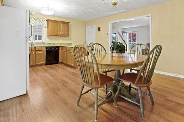 dining room featuring light wood-type flooring, a chandelier, and baseboards