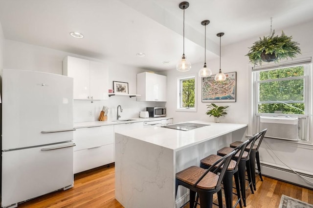 122 W 9th St Unit 2, Boston, MA 02127 - kitchen featuring freestanding refrigerator, healthy amount of natural light, baseboard heating, white cabinetry, and recessed lighting