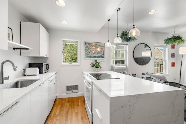 122 W 9th St Unit 2, Boston, MA 02127 - kitchen with white range with electric stovetop, stainless steel microwave, white cabinets, light wood-type flooring, and open shelves
