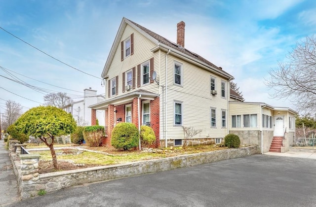 view of front of home featuring a chimney, brick siding, and entry steps