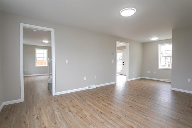 spare room featuring light wood-style floors, visible vents, and baseboards