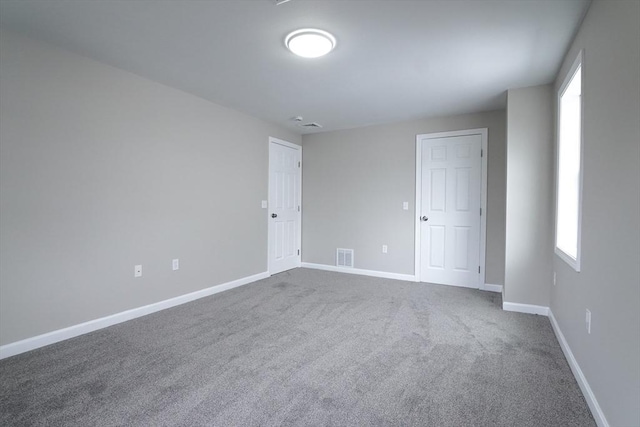 unfurnished room with visible vents, baseboards, and dark carpet