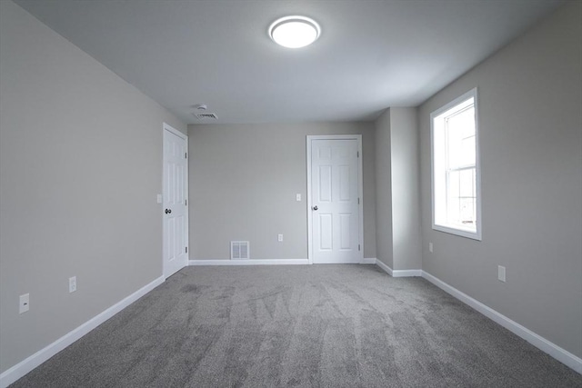 carpeted spare room featuring baseboards and visible vents