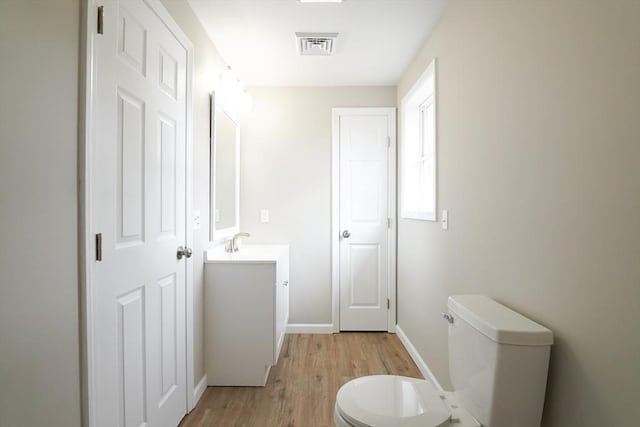 bathroom with vanity, wood finished floors, visible vents, baseboards, and toilet