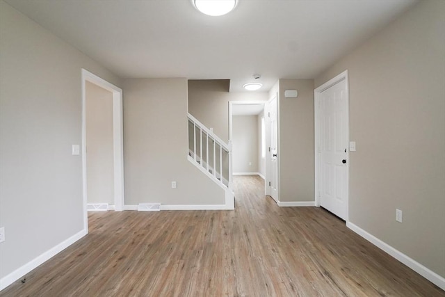 empty room featuring stairway, baseboards, and wood finished floors