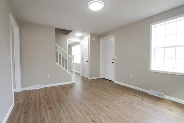 unfurnished room featuring visible vents, light wood-style flooring, stairway, and baseboards