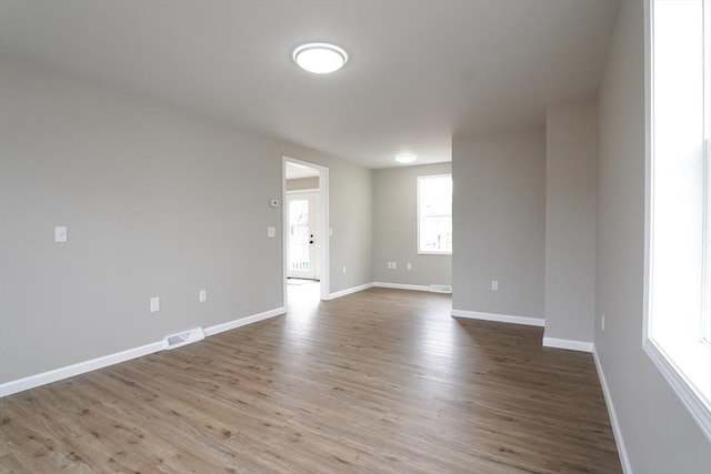 unfurnished room with visible vents, wood finished floors, and baseboards