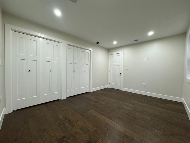 unfurnished bedroom with dark wood-type flooring and two closets