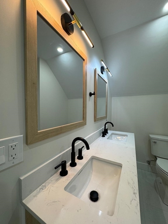 bathroom featuring vanity, lofted ceiling, and toilet