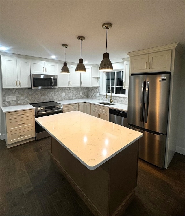 kitchen featuring sink, hanging light fixtures, appliances with stainless steel finishes, a kitchen island, and dark hardwood / wood-style flooring