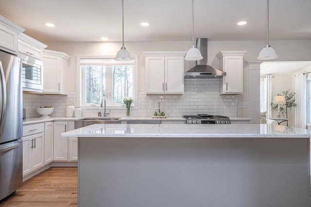 kitchen featuring light stone countertops, pendant lighting, white cabinets, and wall chimney exhaust hood