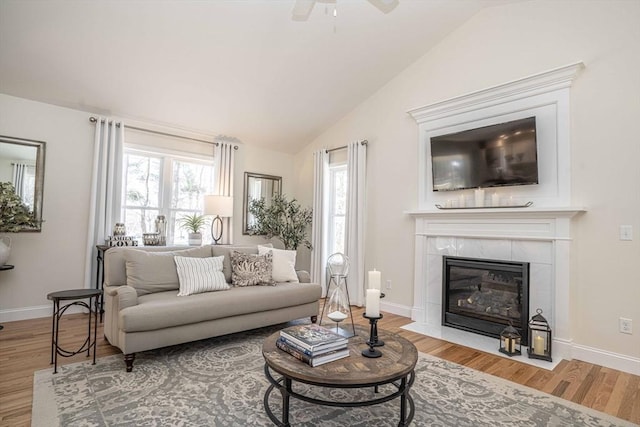 living room with hardwood / wood-style floors, a tile fireplace, and lofted ceiling