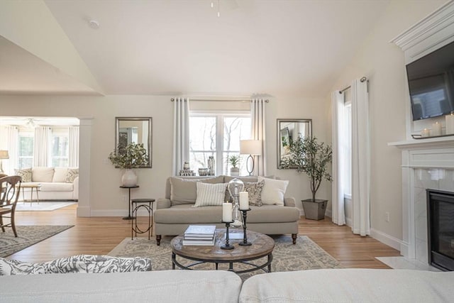 living room with lofted ceiling, a healthy amount of sunlight, a tile fireplace, and light hardwood / wood-style floors